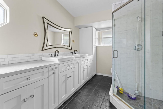 full bath featuring a sink, toilet, double vanity, and a shower stall