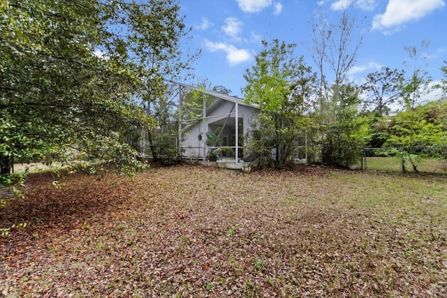 view of yard featuring glass enclosure and fence