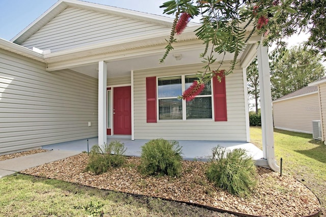 entrance to property with a lawn, covered porch, and central AC