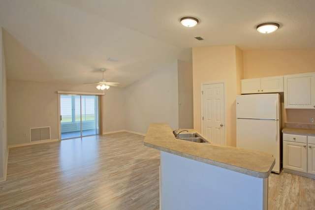 kitchen featuring visible vents, freestanding refrigerator, a sink, vaulted ceiling, and light wood-style floors