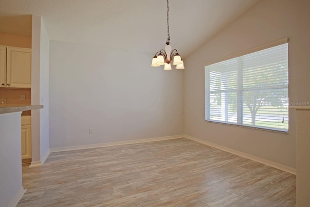 unfurnished dining area featuring light wood finished floors, a notable chandelier, baseboards, and lofted ceiling