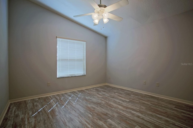 empty room with ceiling fan, baseboards, lofted ceiling, and wood finished floors