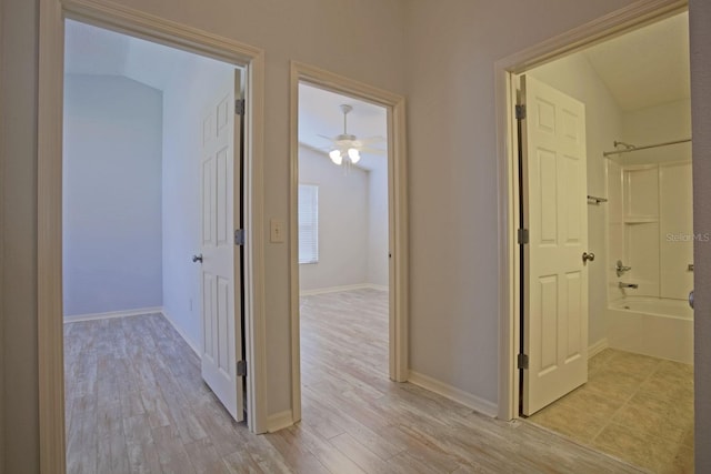 hallway featuring light wood-style flooring and baseboards