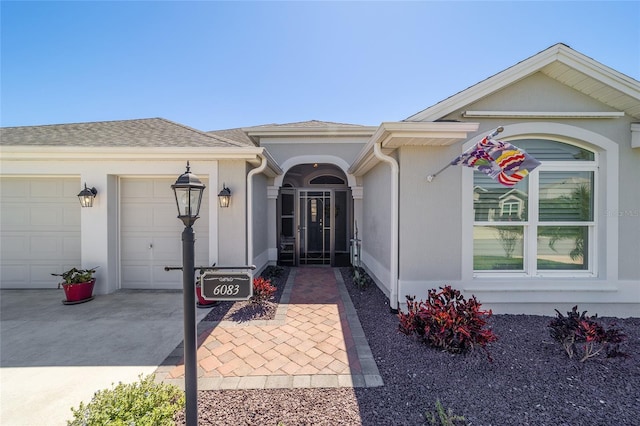 6083 Delphina Loop, The Villages, FL 32163 - entrance to property featuring stucco siding, an attached garage, driveway, and a shingled roof