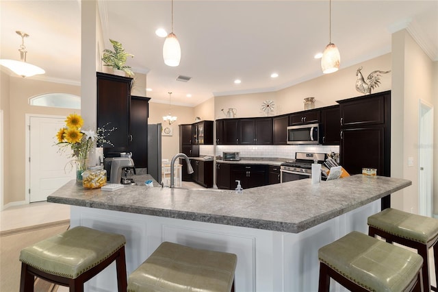 6083 Delphina Loop, The Villages, FL 32163 - kitchen featuring a breakfast bar area, a peninsula, ornamental molding, decorative backsplash, and stainless steel appliances