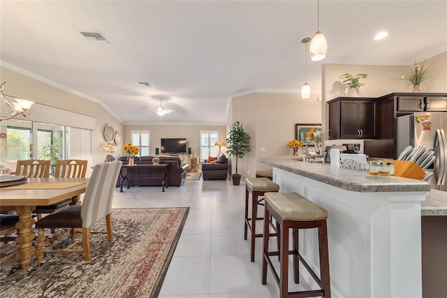 6083 Delphina Loop, The Villages, FL 32163 - kitchen featuring a breakfast bar, ornamental molding, dark brown cabinetry, light tile patterned flooring, and stainless steel fridge with ice dispenser