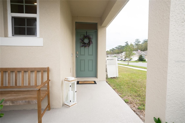 property entrance featuring stucco siding and a yard