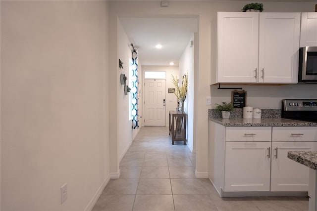 hallway with light tile patterned floors and baseboards