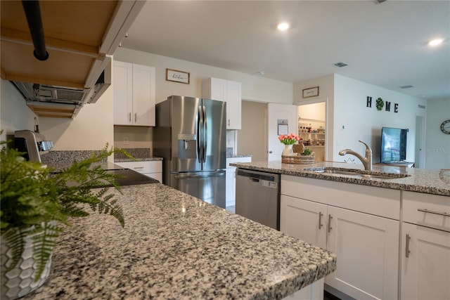 kitchen featuring visible vents, light stone counters, stainless steel appliances, white cabinetry, and a sink