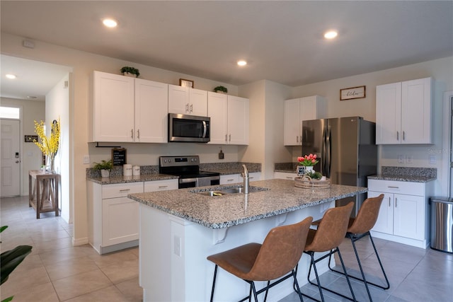 kitchen featuring white cabinets, appliances with stainless steel finishes, a kitchen breakfast bar, and a sink