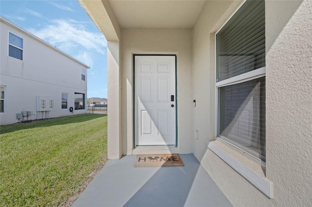 view of exterior entry featuring a yard and stucco siding