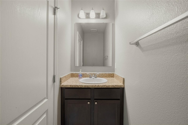 bathroom featuring vanity and a textured wall