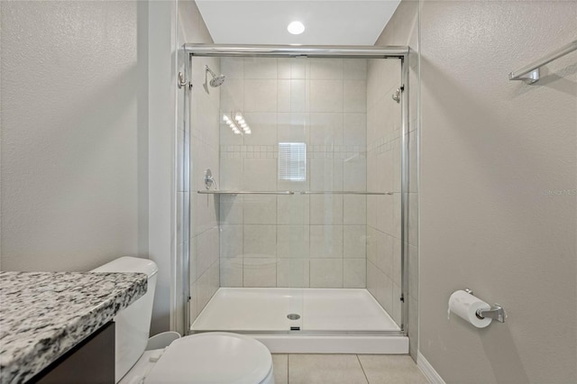 full bath featuring baseboards, toilet, a stall shower, and tile patterned flooring