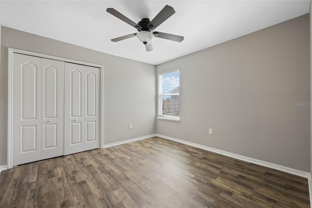 unfurnished bedroom featuring a ceiling fan, wood finished floors, a closet, and baseboards