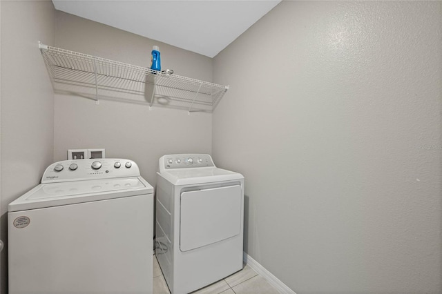 clothes washing area with light tile patterned floors, laundry area, baseboards, and separate washer and dryer