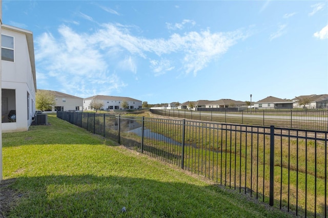 view of yard with central air condition unit, a residential view, and a fenced backyard