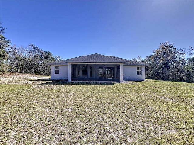 rear view of house featuring stucco siding, a yard, and a sunroom