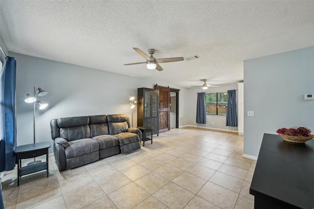 living area featuring visible vents, a barn door, light tile patterned floors, a textured ceiling, and a ceiling fan