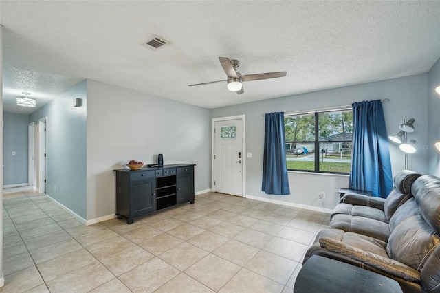 living area featuring light tile patterned flooring, visible vents, a textured ceiling, and ceiling fan