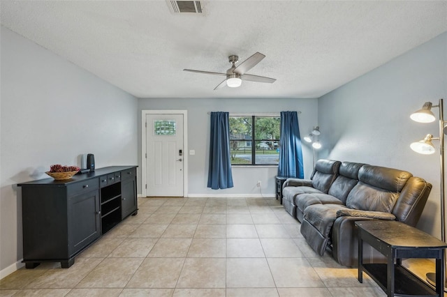 living room featuring light tile patterned floors, visible vents, baseboards, and ceiling fan