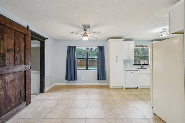 kitchen featuring dishwasher, a barn door, white cabinets, and light countertops