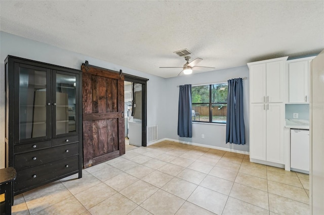 unfurnished bedroom featuring light tile patterned floors, visible vents, and a barn door