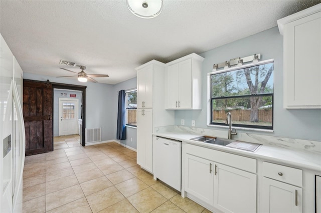 kitchen featuring visible vents, a sink, a barn door, white appliances, and light countertops