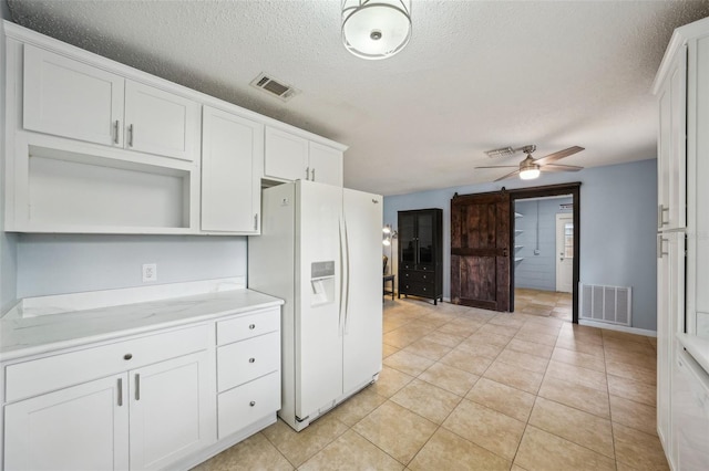 kitchen with ceiling fan, visible vents, white fridge with ice dispenser, and white cabinets