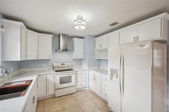 kitchen with visible vents, a sink, white cabinetry, white appliances, and wall chimney range hood