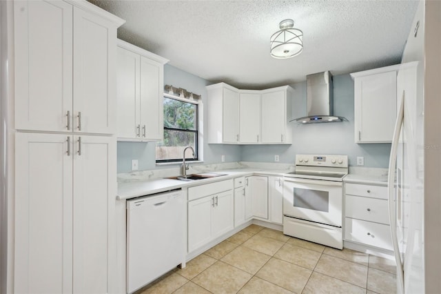 kitchen with white appliances, a sink, light countertops, white cabinetry, and wall chimney range hood