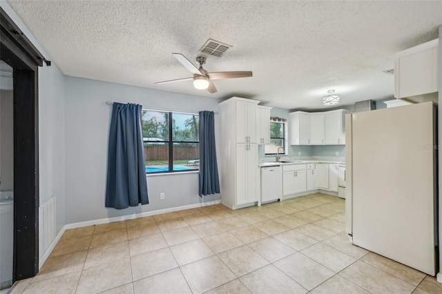 kitchen featuring visible vents, a healthy amount of sunlight, white appliances, and light countertops