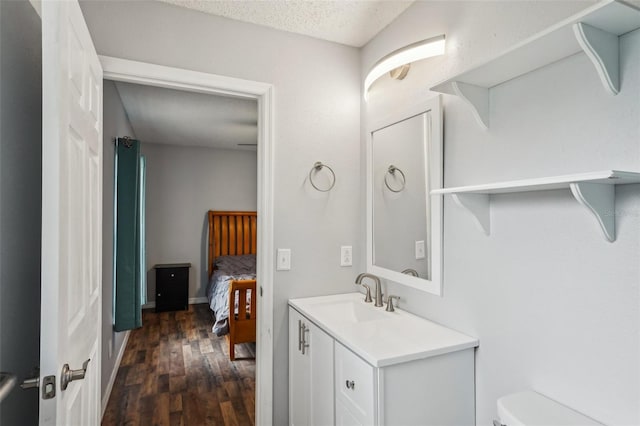 bathroom with toilet, a textured ceiling, wood finished floors, baseboards, and vanity