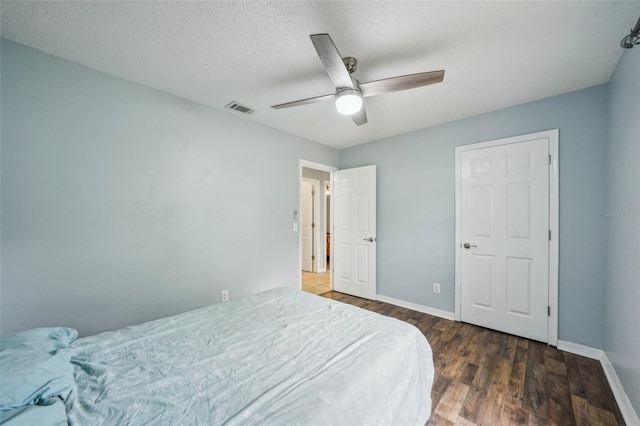 bedroom featuring visible vents, a textured ceiling, wood finished floors, baseboards, and ceiling fan