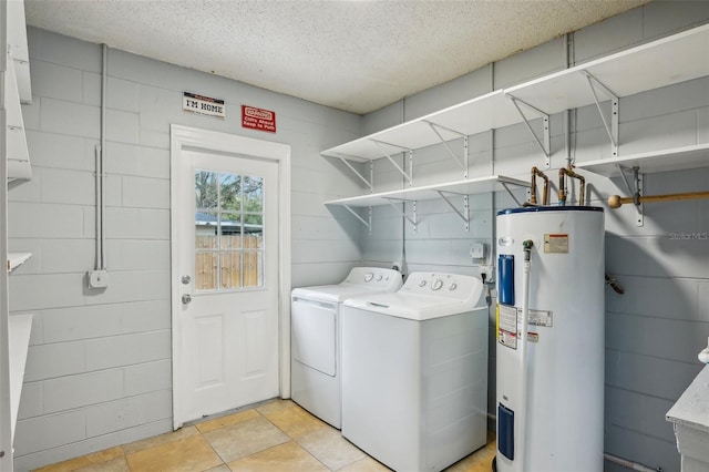 washroom featuring a textured ceiling, electric water heater, laundry area, and washer and clothes dryer