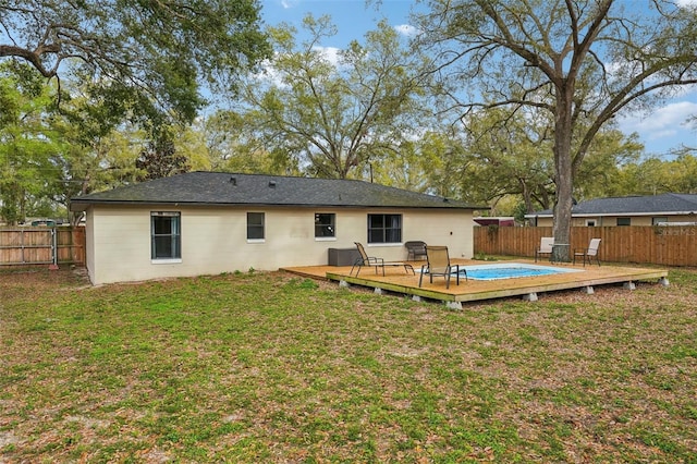 rear view of property featuring a deck, a lawn, and a fenced backyard