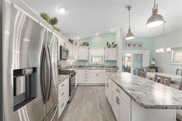3786 Stephanie Way, The Villages, FL 32163 - kitchen with a kitchen island, lofted ceiling, a sink, white cabinets, and appliances with stainless steel finishes