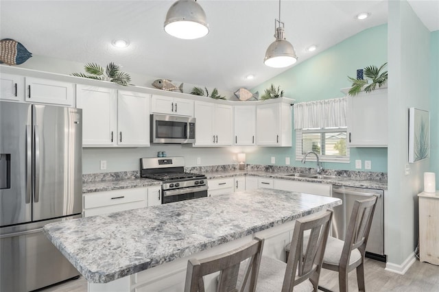 3786 Stephanie Way, The Villages, FL 32163 - kitchen with lofted ceiling, a sink, appliances with stainless steel finishes, white cabinetry, and a kitchen breakfast bar