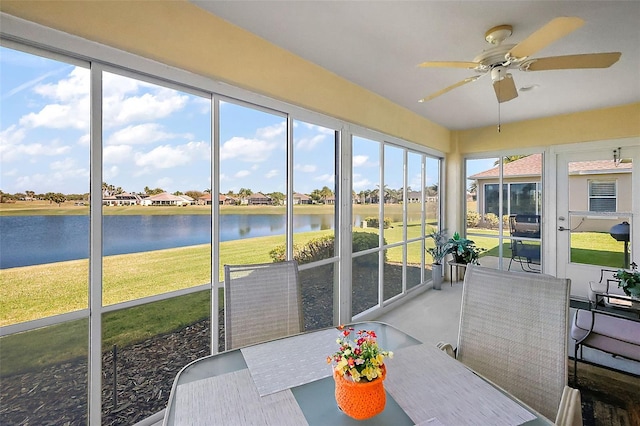 sunroom with a ceiling fan and a water view