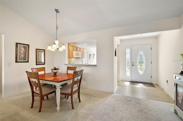 dining space featuring vaulted ceiling, a notable chandelier, and light carpet