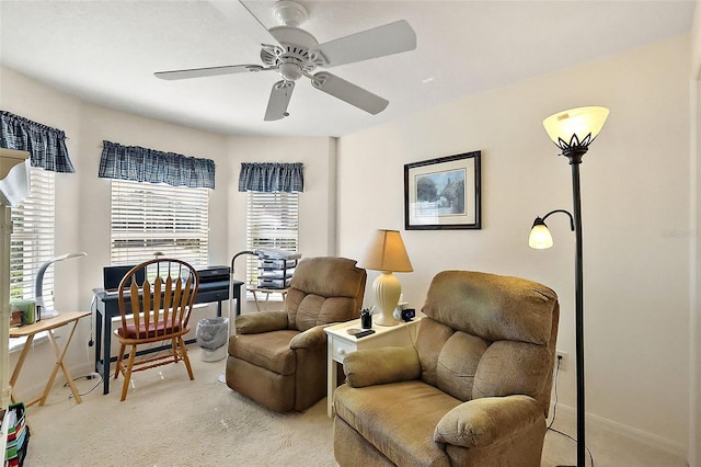 living area featuring light colored carpet, baseboards, and ceiling fan