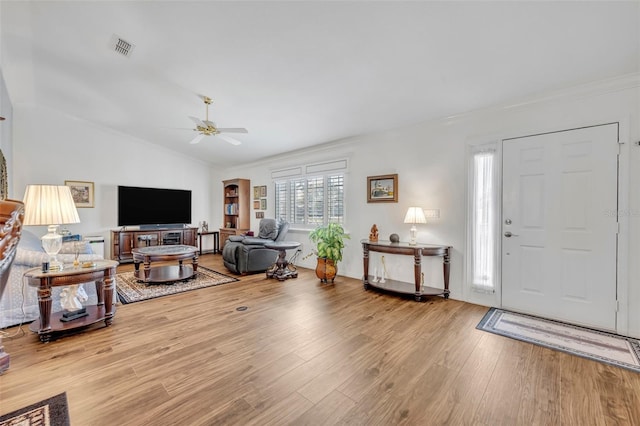 living room featuring visible vents, ceiling fan, lofted ceiling, ornamental molding, and wood finished floors