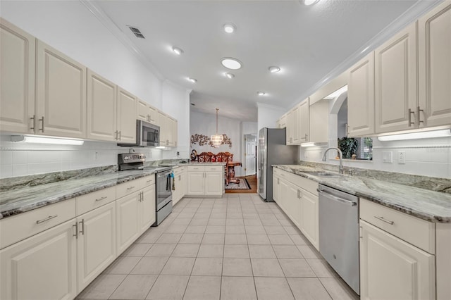 kitchen with visible vents, a sink, decorative backsplash, ornamental molding, and stainless steel appliances