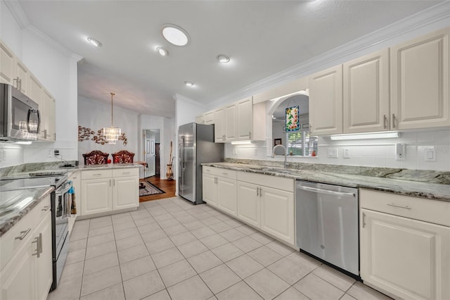 kitchen with crown molding, light stone counters, white cabinets, stainless steel appliances, and a sink