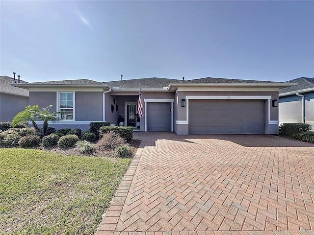 view of front of property featuring stucco siding, decorative driveway, a front lawn, and an attached garage