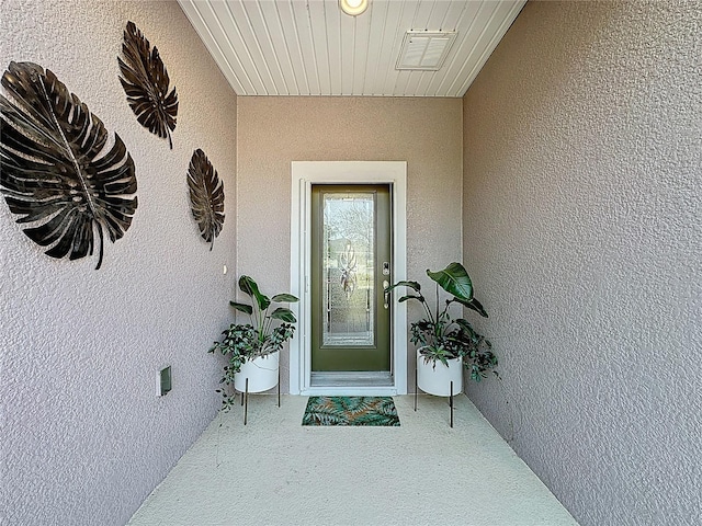 doorway to property with visible vents and stucco siding