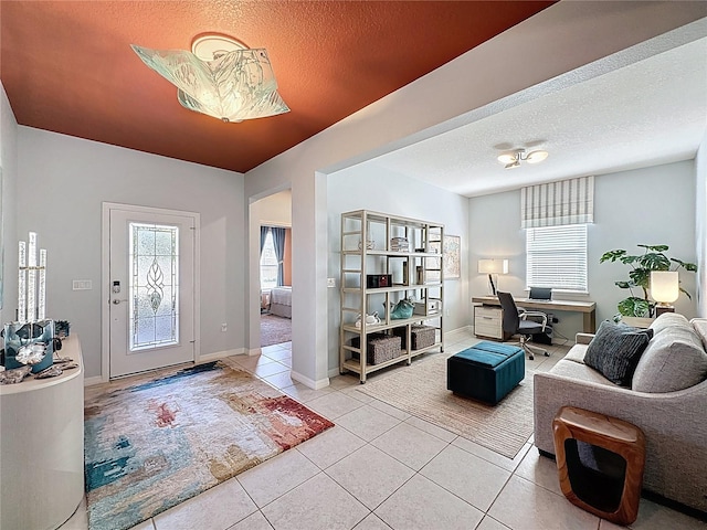 entrance foyer with tile patterned floors, baseboards, plenty of natural light, and a textured ceiling