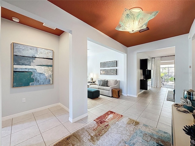 hallway featuring tile patterned floors, baseboards, and a textured ceiling