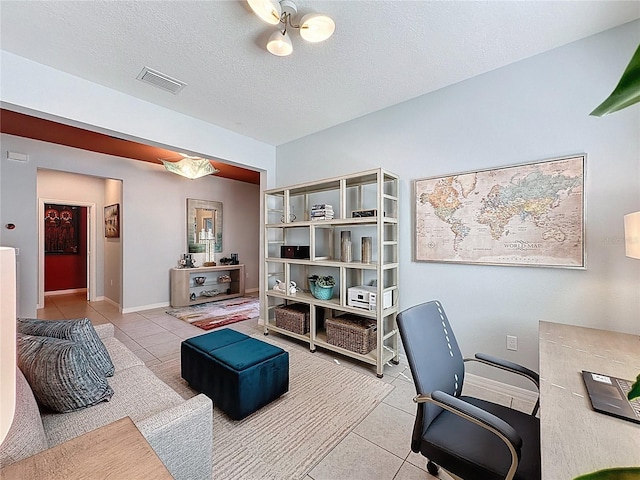 tiled office featuring visible vents, baseboards, and a textured ceiling