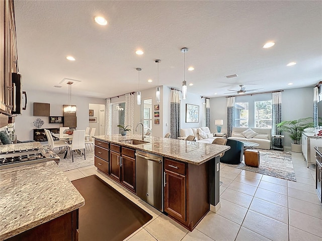 kitchen featuring an island with sink, a sink, dark brown cabinets, appliances with stainless steel finishes, and open floor plan