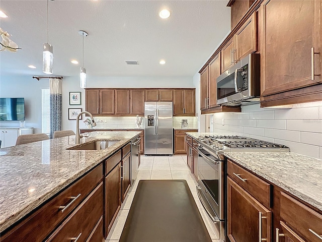 kitchen with visible vents, stone counters, decorative backsplash, stainless steel appliances, and a sink